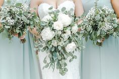 the bridesmaids are holding their bouquets with white flowers and greenery on them