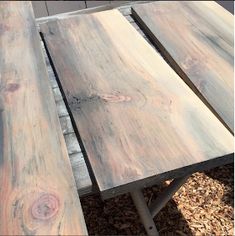 two wooden tables sitting next to each other on top of mulch covered ground in front of a building