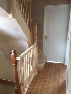 an empty room with wooden floors and white door on the far wall, next to a set of stairs