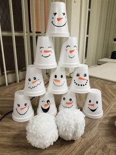 a group of snowmen made out of cups sitting on top of a wooden table