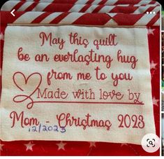 a red and white striped table cloth with an embroidered message on the side that says, may this quilt be everlasting hug from me to you made with love by mom