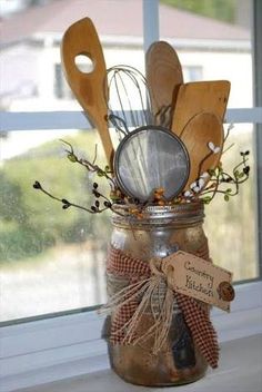 a mason jar filled with wooden spoons and utensils sitting on top of a window sill