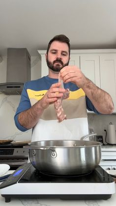 a man standing in a kitchen preparing food on top of a metal pan with a spatula