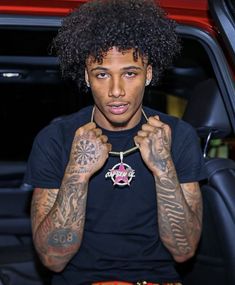 a man with tattoos on his arms sitting in a car