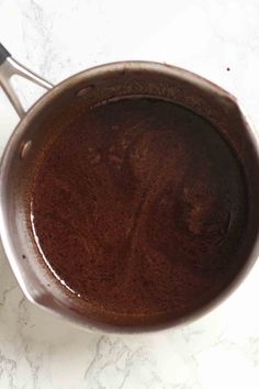 a saucepan filled with brown liquid on top of a white counter