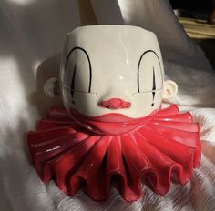 a red and white clown mask sitting on top of a bed