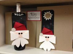 two paper santas are sitting on top of a shelf next to some wine bottles