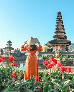 a woman in an orange dress and hat looking at the pagodas