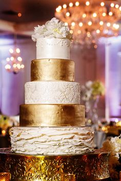 a white and gold wedding cake sitting on top of a table