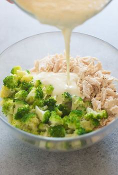 someone is pouring dressing over broccoli in a glass bowl on the counter top