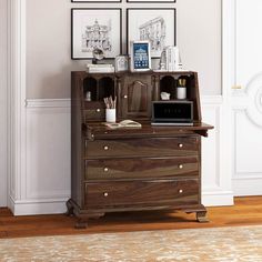 a wooden desk with two pictures on the wall above it and a microwave in front of it