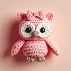 a crocheted pink owl sitting on top of a pink surface