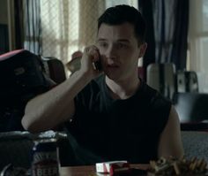 a man talking on a cell phone while sitting at a table in a living room