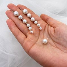 a person holding three pairs of pearls in their hand