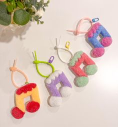 four felt ornaments are hanging on a white table next to a potted plant and scissors