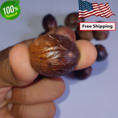 a hand holding an unpeeled nut with the american flag in the background