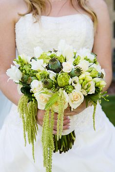 a bride holding a bouquet of white and green flowers