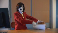 a woman dressed as mime in an office with makeup on her face and hands