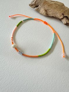 - Embrace the vibrant spirit of summer with this stunning handmade anklet, featuring an adjustable neon orange cord and an array of colourful beads. This unique piece is designed to add a pop of colour to any outfit and is perfect for beach days, festivals, or casual wear. - Materials: Neon orange cord, aqua, green, orange, and white tiny beads, a mother of pearl bead, and striped Czech glass beads. - Design: The anklet showcases a beautiful combination of colours and textures. The neon orange c Handmade Anklets, Sliding Knot Closure, Tiny Beads, Anklet Jewelry, Body Jewellery, Aqua Green, Neon Orange, White Beads, Czech Glass Beads