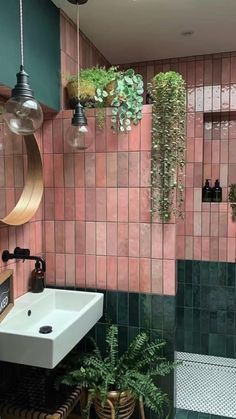 a bathroom with green and pink tiles on the walls, potted plants hanging from the ceiling