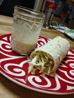 a burrito on a red plate with a jar of peanut butter next to it