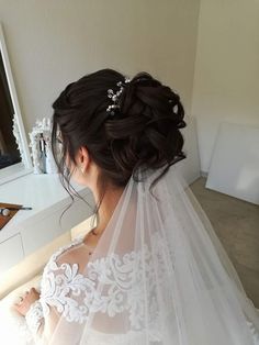 a woman in a wedding dress looking at herself in the mirror while wearing a veil