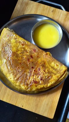 an omelet on a plate next to a bowl of sauce