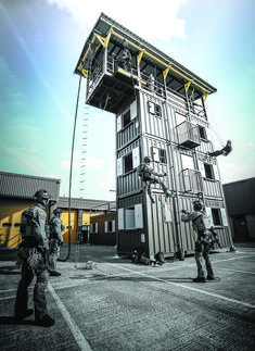 two men standing in front of a tall building with a ladder on it's side