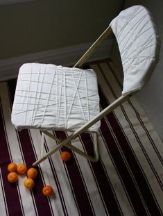 a white chair sitting on top of a striped rug next to oranges in the floor