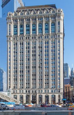 a tall building with many windows in front of a city street and cars on the road