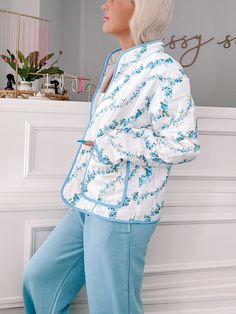 Wrap yourself in floral perfection with the Blue Floral Crest Quilted Jacket from Sassy Shortcake. This ivory, quilted jacket features a playful blue floral pattern and side pockets, all finished off with a blue lined hem. Stay warm and stylish in this fun jacket. content: 100% nylon care: hand wash cold fits true to size, model wearing size small Blue Floral Print Cotton Outerwear, Blue Cotton Floral Print Outerwear, Spring Floral Print Outerwear For Loungewear, Blue Outerwear For Spring Loungewear, White Quilted Jacket For Spring, White Quilted Jacket With Pockets For Spring, Blue Quilted Spring Outerwear, Sassy Shortcake, Fun Jacket