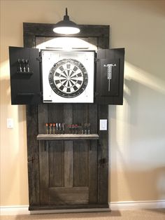 a dart board mounted to the side of a wooden cabinet with darts on it,