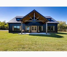 a large black house sitting on top of a lush green field