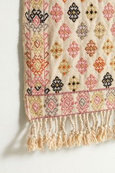 an old rug hanging on the wall with fringes and tassels around it