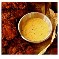 a metal bowl filled with sauce next to fried food