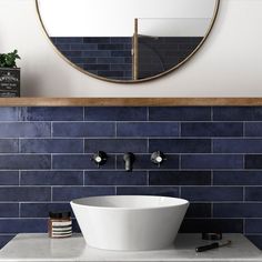 a bathroom sink sitting under a round mirror next to a wall mounted faucet