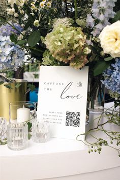 a table topped with flowers and candles next to a sign that says capture the love