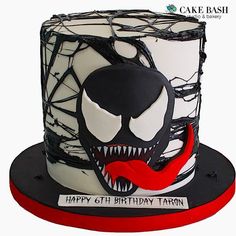 a spiderman birthday cake is decorated with black and white icing