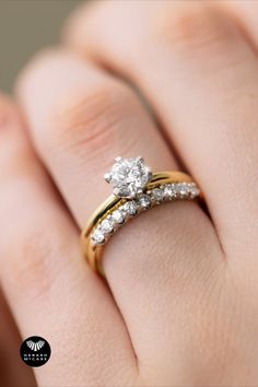 a woman's hand with two wedding rings on top of her finger and the ring has a diamond in it