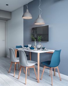 a dining table with four chairs and a television mounted on the wall above it in a room