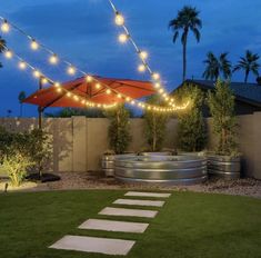 an outdoor patio with lights strung over it and a fire pit in the middle of the yard