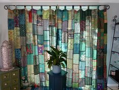 a potted plant sitting on top of a table next to a window covered in colorful fabric