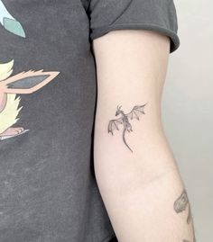 a woman's arm with a small dragon tattoo on the left side of her arm