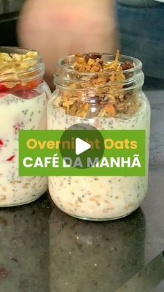 two jars filled with food sitting on top of a counter next to a person's hand