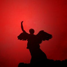 an angel silhouetted against a red background