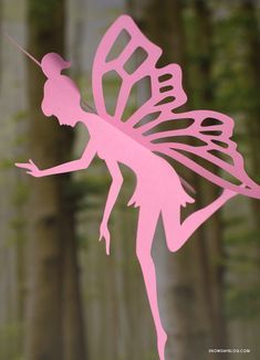 a pink paper cut out of a fairy holding a wand in front of some trees