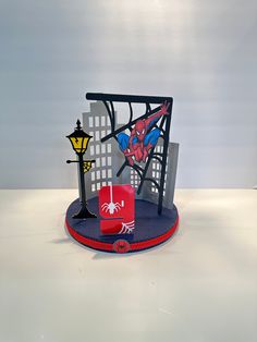 a red candle sits on top of a blue plate next to a spiderman sculpture