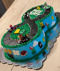 two cakes decorated with cars and farm animals on a wooden table, ready to be eaten