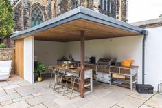 an outdoor kitchen with tables and chairs under a covered area in front of a church