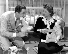 a man and woman are playing with babys in their bedroom while the child sits on the floor